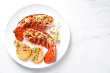 Limonlu ıstakoz kuyruğu, yeşil yeşil soğan ve beyaz mermer masa, üst manzara. Metin için boşluk