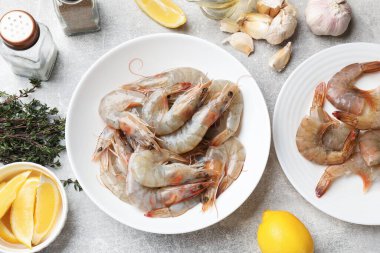 Gri masada taze çiğ karides ve baharatlar, düz yatıyordu.