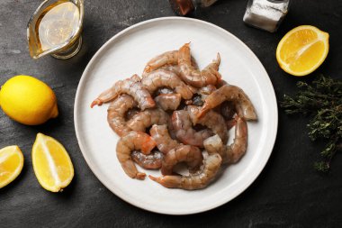 Gri masada taze çiğ karides, baharat ve limon var.