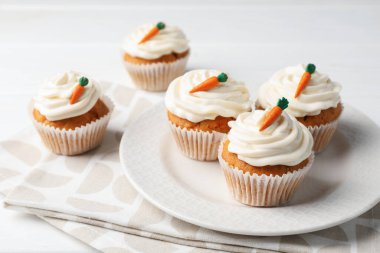 Beyaz ahşap masada kremalı havuçlu kekler, yakın plan.