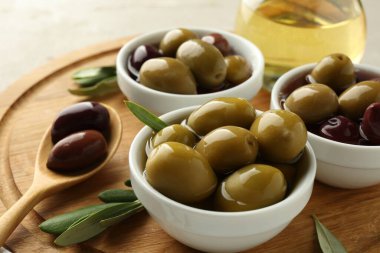 Lezzetli marine edilmiş zeytinler kaseler, kaşık, yağ ve yeşil yapraklar masada, yakın çekim