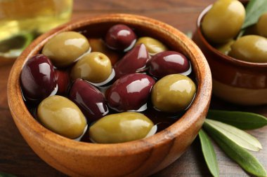 Lezzetli zeytinyağı, yağ ve yapraklar ahşap masada, yakın plan.