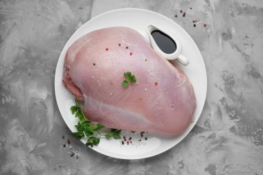 Çiğ hindi göğsü, soya sosu, maydanoz ve biber taneleri gri desenli masa, üst manzara.