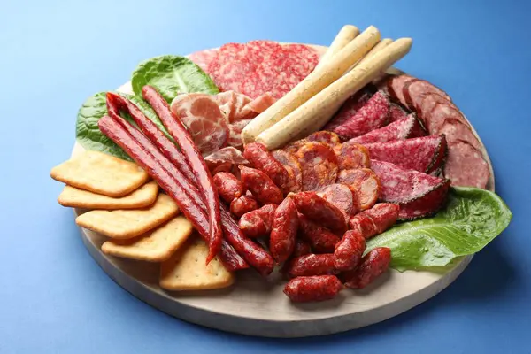 Mavi arka planda farklı tütsülenmiş sosisler ve diğer atıştırmalıklar, yakın plan