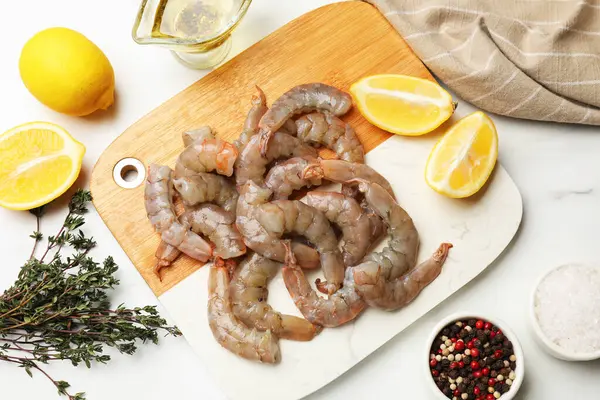 Taze çiğ karidesler, baharatlar ve limonlar beyaz mermer masa üzerinde, düz yatıyordu.