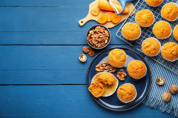 Lezzetli havuçlu kekler, cevizler ve taze sebzeler mavi ahşap masada, düz uzanmış. Metin için boşluk