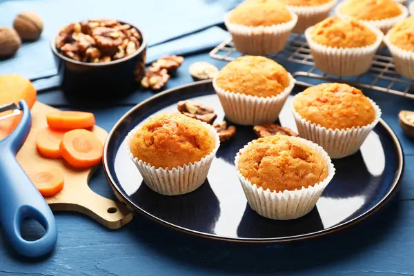 Lezzetli havuçlu kekler, cevizler ve taze sebzeler mavi ahşap masada, yakın plan.