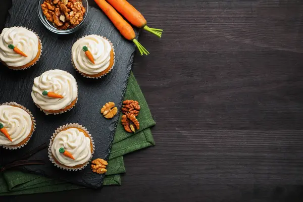 Kremalı havuçlu kekler, cevizler ve taze sebzeler siyah ahşap masada, düz bir şekilde. Metin için boşluk