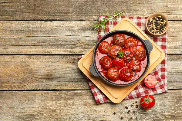 Fırın kabında domates soslu leziz köfteler ve ahşap masa üzerinde baharatlar. Metin için boşluk