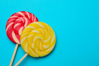 Açık mavi arka planda leziz lolipoplar, düz yatış. Metin için boşluk