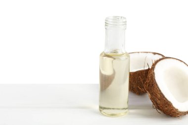 Cam şişede pişen organik hindistan cevizi yağı ve beyaz arka planda ahşap masada yarım meyve.