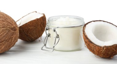 Kavanozda organik hindistan cevizi pişirme yağı ve tahta masada beyaz arka planda taze meyveler.