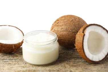 Cam kavanozda organik hindistan cevizi pişirme yağı ve tahta masada beyaz arka planda taze meyveler.