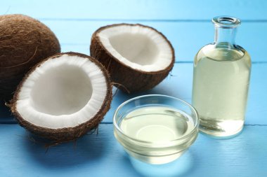 Organik hindistan cevizi pişirme yağı ve açık mavi ahşap masada taze meyveler, yakın plan.