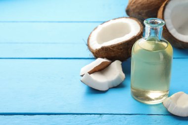 Cam şişede pişen organik hindistan cevizi yağı ve açık mavi ahşap masada taze meyveler.