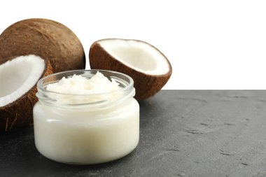 Cam kavanozda organik hindistan cevizi pişirme yağı ve beyaz arka planda siyah masada taze meyveler.