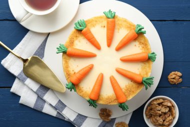 Lezzetli ev yapımı havuçlu kek mavi ahşap masada servis ediliyor.