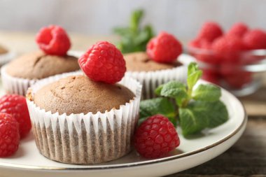 Ahududulu lezzetli kekler ve ahşap masada nane şekeri, yakın plan.
