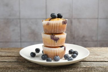 Yaban mersinli lezzetli çörekler ahşap masada gri fayanslı arka planda, yakın planda