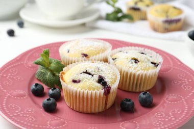 Yaban mersinli lezzetli kekler, pudra şekeri ve nane şekeri beyaz masada, yakın plan.