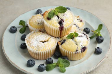 Yaban mersinli lezzetli kekler, pudra şekeri ve nane şekeri gri desenli masa, yakın plan.