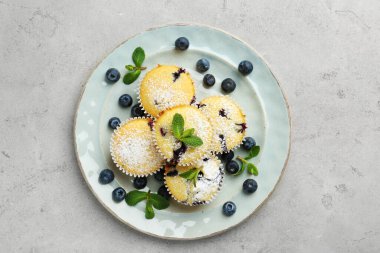 Yaban mersinli lezzetli kekler, pudra şekeri ve nane şekeri gri desenli masa, üst manzara.