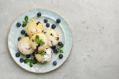 Yaban mersinli lezzetli kekler, pudra şekeri ve gri desenli masada nane şekeri, üst manzara. Metin için boşluk