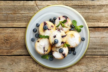 Yaban mersinli lezzetli çörekler, pudra şekeri ve nane şekeri ahşap masa, üst manzara