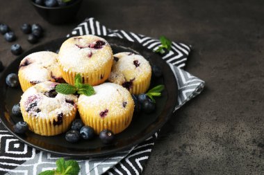 Yaban mersinli lezzetli çörekler, pudra şekeri ve siyah desenli masada nane şekeri, yakın plan. Metin için boşluk