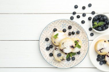 Yaban mersinli lezzetli çörekler, pudra şekeri ve beyaz ahşap masada nane şekeri, düz yatak. Metin için boşluk