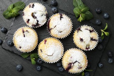 Yaban mersinli lezzetli çörekler, pudra şekeri ve siyah desenli masada nane şekeri.