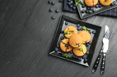 Yaban mersinli lezzetli kekler, nane ve çatal bıçak seti koyu dokulu masa, düz yatak. Metin için boşluk