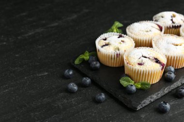 Yaban mersinli lezzetli çörekler, pudra şekeri ve siyah desenli masada nane şekeri, yakın plan. Metin için boşluk