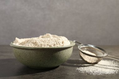 Kahverengi pirinç unu ve elek gri masada. Metin için boşluk