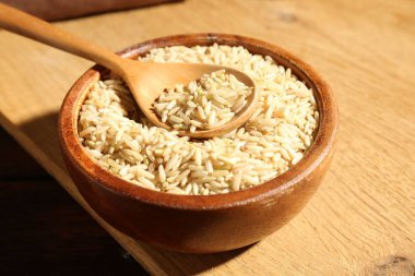 Kahverengi pirinç ve kaşık kasede, ahşap masada, yakın plan.