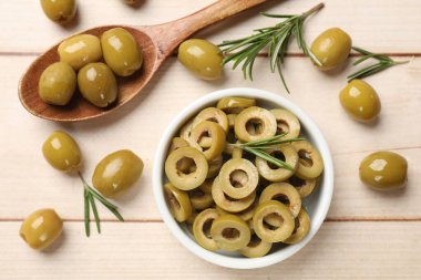 Lezzetli salamura edilmiş zeytin halkaları, kaşık dolusu ve biberiye açık ahşap masada, düz uzanmış.