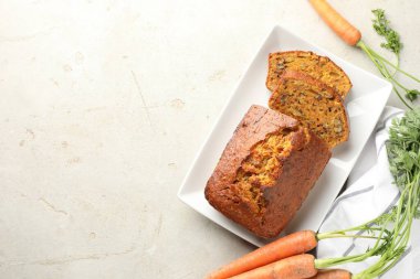 Açık gri masada fındıklı ve sebzeli ev yapımı havuçlu kek. Metin için boşluk