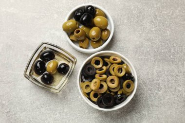 Farklı lezzetlerde marine edilmiş zeytin halkaları, gri desenli masadaki bütün halkalar, düz uzanmış.