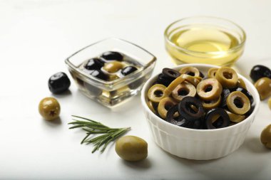 Farklı lezzetlerde marine edilmiş zeytin halkaları, bütün halkalar, biberiye ve yağ ışıklı masada, yakın plan.