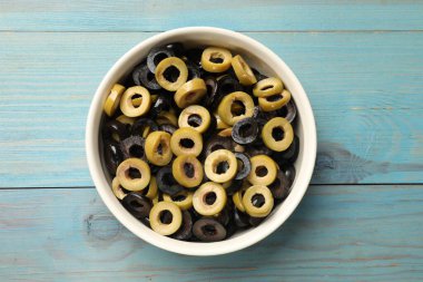 Farklı leziz zeytin halkaları açık mavi ahşap masada, üst tarafta.