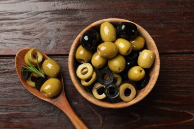 Farklı lezzetlerde marine edilmiş zeytin halkaları ve ahşap masadaki bütün halkalar, düz uzanış