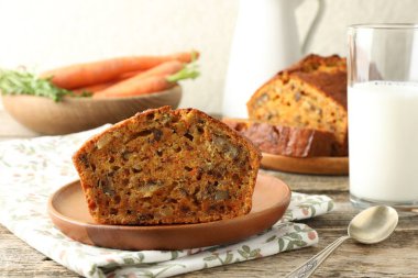 Ev yapımı havuçlu kek, fındıklı, sütlü, sebzeli ve kaşıklı ahşap masa, yakın plan.