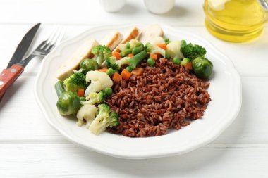 Sebzeli lezzetli kahverengi pirinç ve beyaz ahşap masada tavuk, yakın plan.