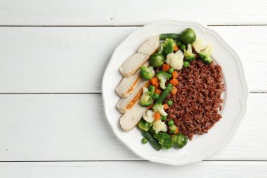 Sebzeli kahverengi pirinç ve beyaz ahşap masada tavuk, üst manzara. Metin için boşluk