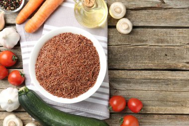 Tabaktaki çiğ kahverengi pirinç ahşap masadaki taze ürünlerin arasında, düz yerde. Metin için boşluk