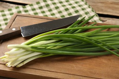 Taze yeşil soğan ve bıçak masanın üstünde, yakın plan.