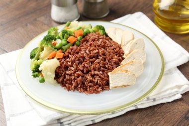 Tahta masada servis edilen tavuk ve sebzeli lezzetli kahverengi pirinç.