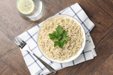 Ahşap masada servis edilen maydanozlu lezzetli kahverengi pirinç.