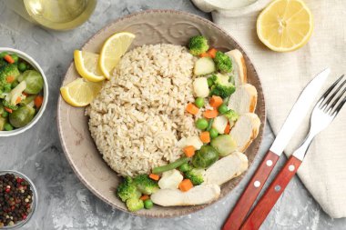 Gri desenli masada servis edilen tavuk, sebze ve limon dilimli lezzetli kahverengi pirinç.