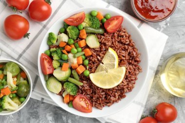 Gri desenli masada servis edilen sebzeli ve limon dilimli lezzetli kahverengi pirinç.